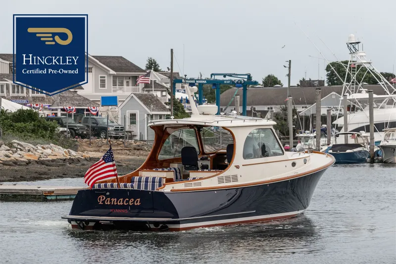 The Image of Hinckley Picnic Boat MKIII 2012 cruising in a marina, certified pre-owned, with American flag. - 0