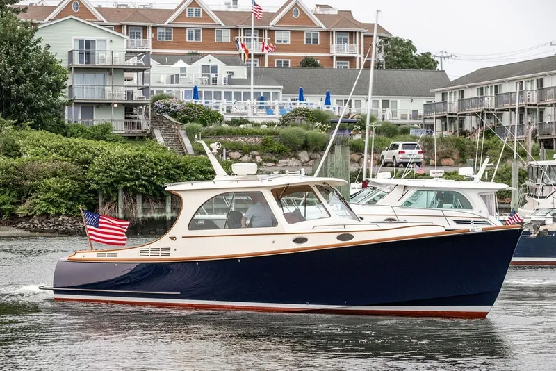 Slide: The Image of Hinckley Picnic Boat MKIII 2012 cruising near waterfront buildings, displaying American flag. - 7