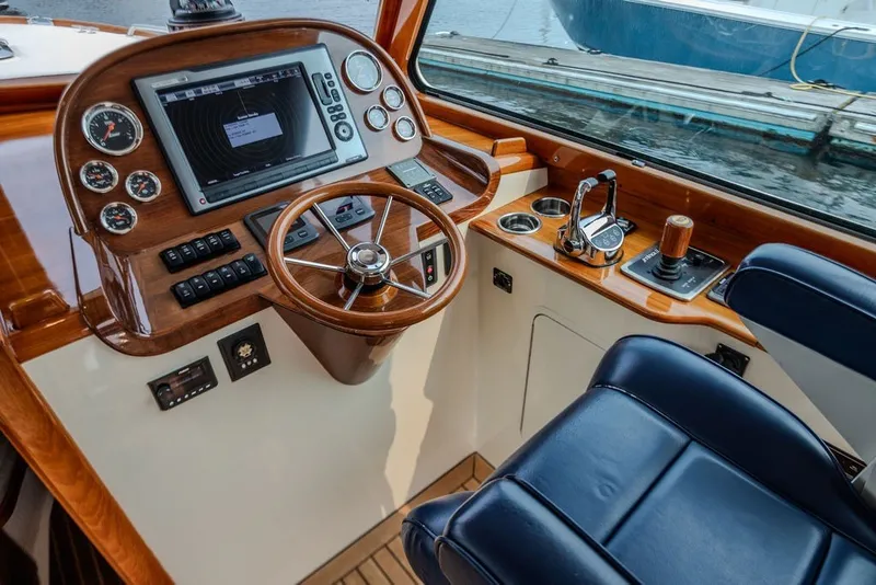 Slide: The Image of Hinckley Picnic Boat MKIII 2012 helm with wooden dashboard, steering wheel, and navigation controls. - 33