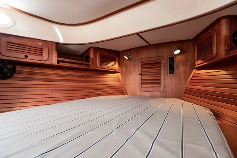 Slide: The Image of Interior cabin of 2012 Hinckley Picnic Boat MKIII with wooden paneling and striped bedding. - 19