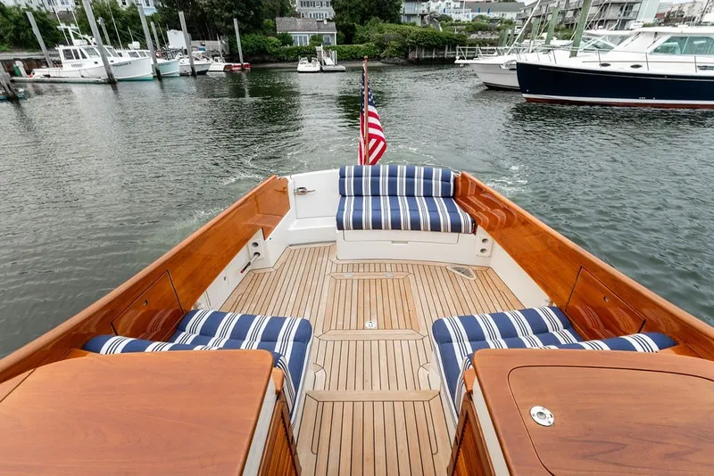 Slide: The Image of Hinckley Picnic Boat MKIII 2012 with striped seating, wooden deck, and American flag on calm water. - 27