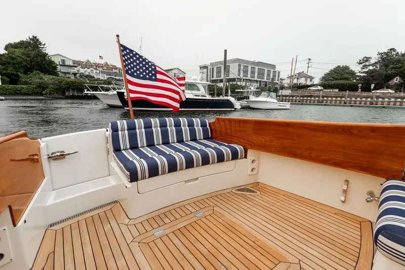 Slide: The Image of 2012 Hinckley Picnic Boat MKIII with striped seating and American flag on deck. - 28