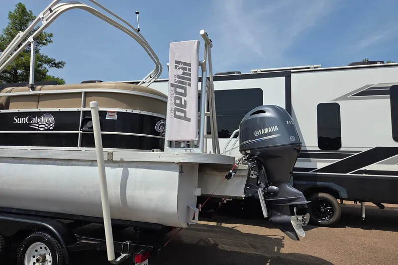 Slide: The Image of SunCatcher V22 RC 2015 pontoon boat with Yamaha motor, parked beside an RV. - 7