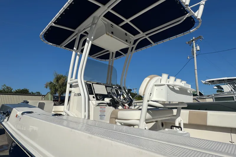 Slide: The Image of 2023 Robalo R200 Center Console boat with T-top and helm station, under clear blue sky. - 7