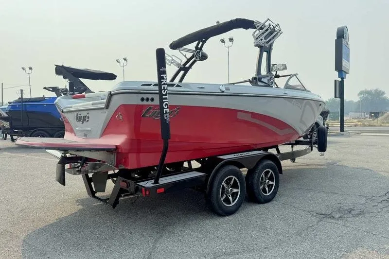 Slide: The Image of 2018 Tigé R21 boat on trailer, red and gray, parked outdoors. - 7