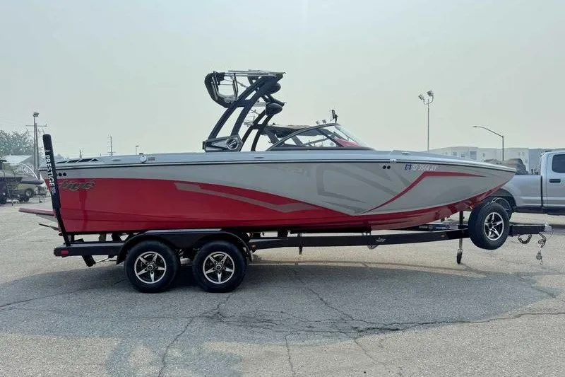 Slide: The Image of 2018 Tigé R21 boat on trailer, red and gray design, parked outdoors. - 10