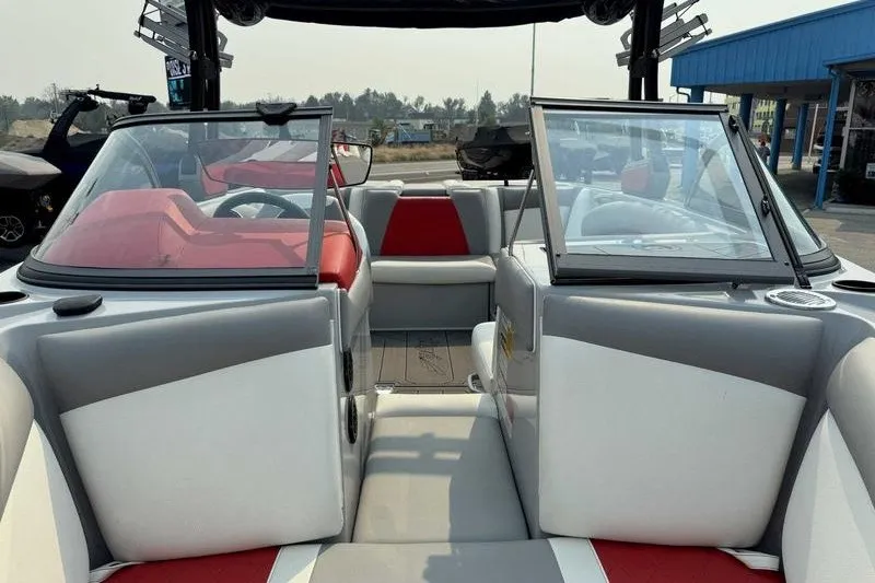 Slide: The Image of 2018 Tigé R21 boat interior with red and gray seating, open windshield, and outdoor setting. - 5