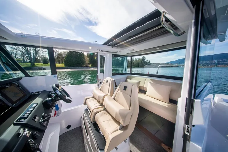 Slide: The Image of 2027 Axopar 29 XC Cross Cabin interior with plush seating and scenic water view. - 11