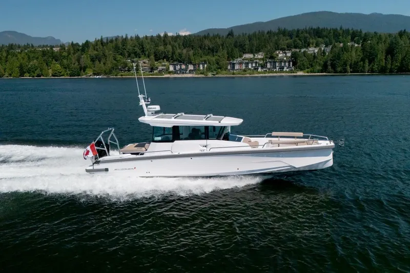 The Image of 2027 Axopar 29 XC Cross Cabin cruising on a scenic lake with forested hills. - 1