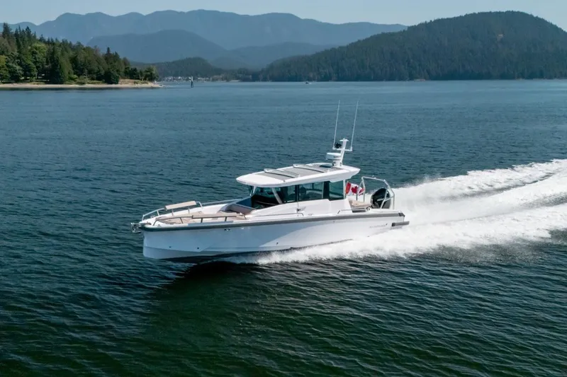 Slide: The Image of 2027 Axopar 29 XC Cross Cabin cruising on a scenic lake with forested hills. - 5