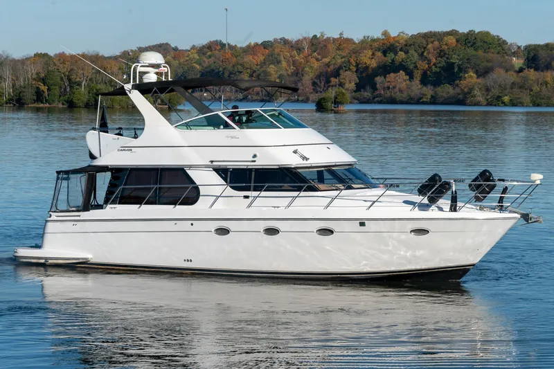 Slide: The Image of 2000 Carver 450 Voyager Pilothouse yacht on a serene lake with autumn trees. - 6