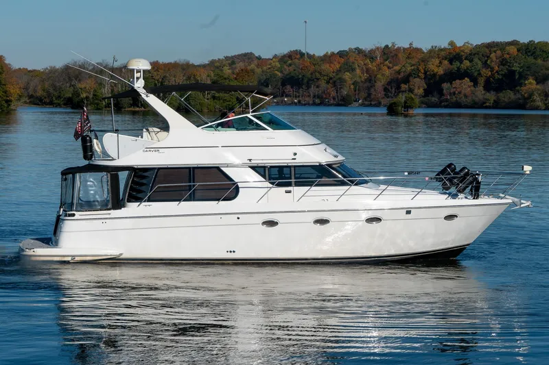 Slide: The Image of 2000 Carver 450 Voyager Pilothouse yacht on a serene lake with autumn foliage. - 5