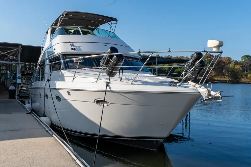 Slide: The Image of 2000 Carver 450 Voyager Pilothouse yacht docked by a serene lake. - 7