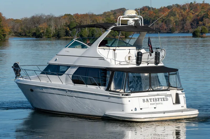Slide: The Image of 2000 Carver 450 Voyager Pilothouse yacht on a serene lake with autumn trees. - 2