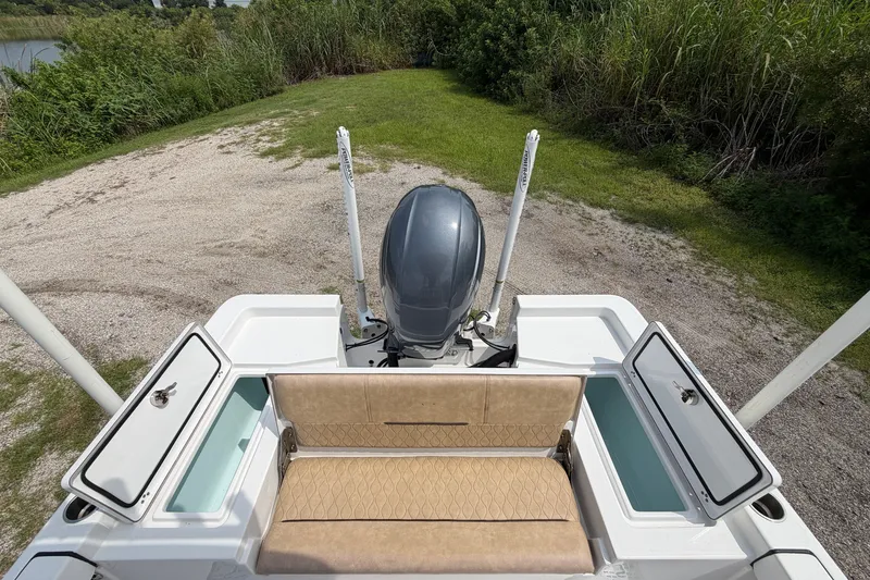 Slide: The Image of 2019 Sportsman Masters 227 Bay Boat with open storage compartments and motor, parked on grass. - 9