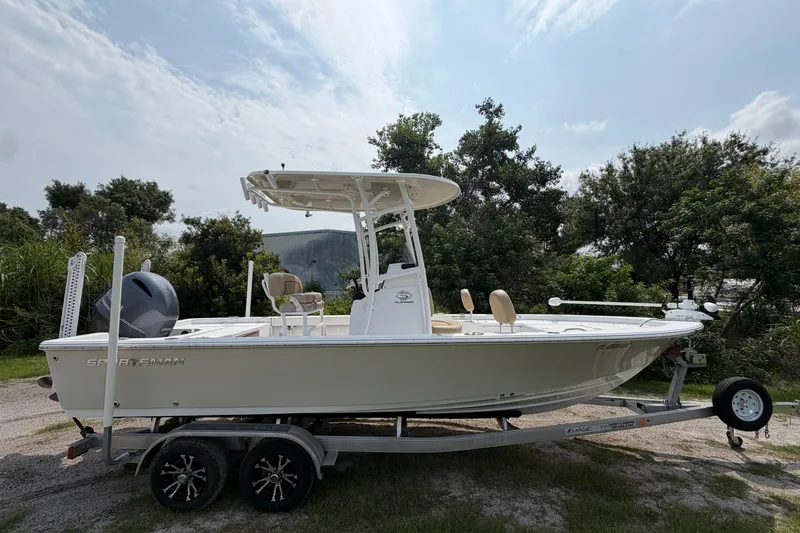Slide: The Image of 2019 Sportsman Masters 227 Bay Boat on trailer, parked outdoors with trees in background. - 1