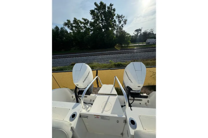 Slide: The Image of 2026 World Cat 295 CC boat with dual Mercury engines, parked near railway tracks. - 13