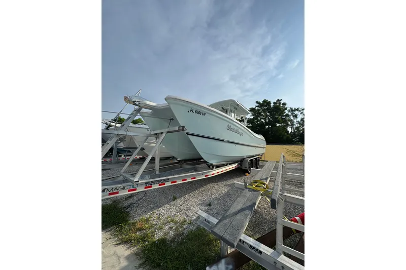 Slide: The Image of 2026 World Cat 295 CC boat on trailer, parked outdoors under a clear sky. - 2