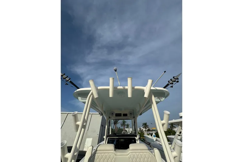 Slide: The Image of 2026 World Cat 295 CC boat with fishing rod holders under a clear sky. - 14