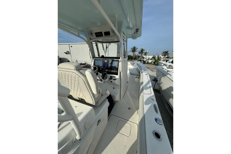 Slide: The Image of 2026 World Cat 295 CC boat interior with modern helm and seating, parked outdoors. - 8