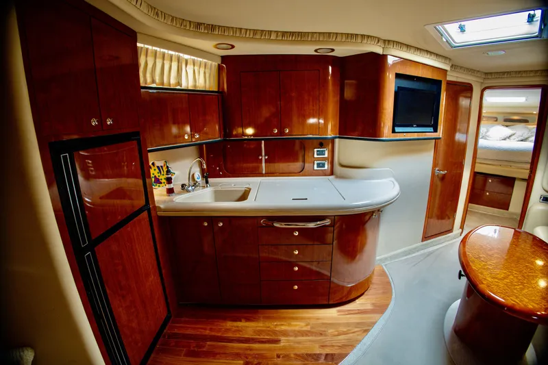 Slide: The Image of The interior of a 2003 Sea Ray Sundancer 460 features an elegant kitchen with wooden cabinets. - 19