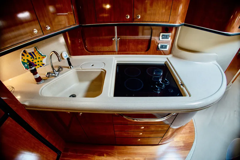 Slide: The Image of The 2003 Sea Ray Sundancer 460 galley features a sleek countertop, cooktop, and wooden cabinetry. - 21