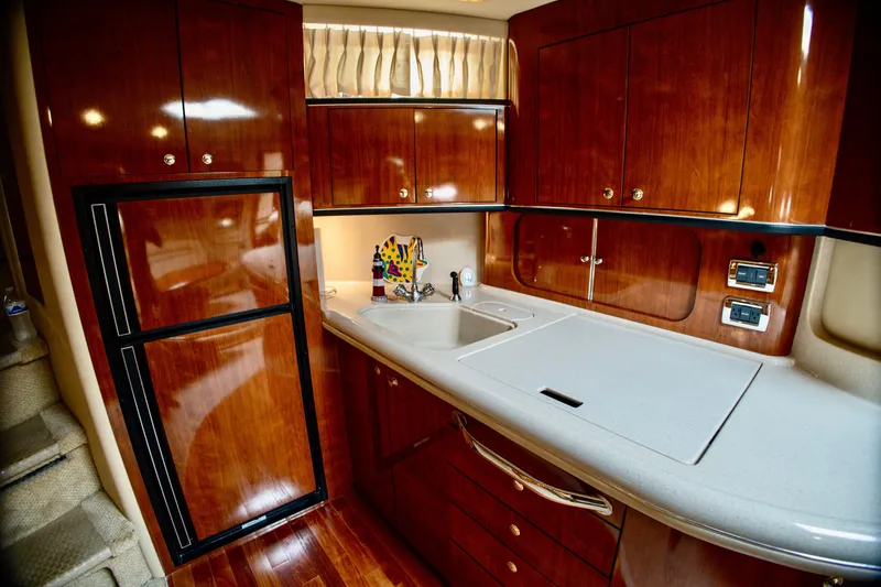 Slide: The Image of The 2003 Sea Ray Sundancer 460's galley features glossy wood cabinets and modern appliances. - 20
