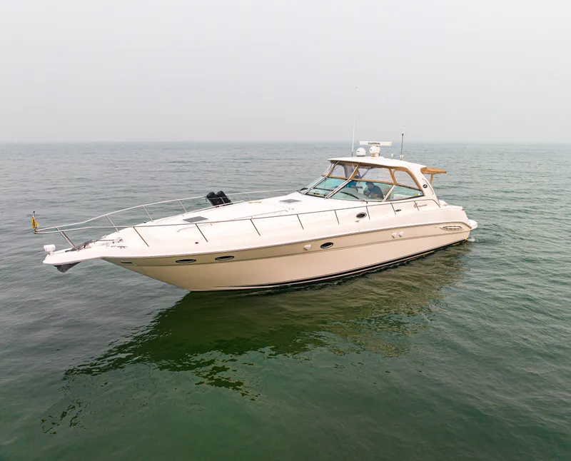 Slide: The Image of A 2003 Sea Ray Sundancer 460 on calm water. It features a sleek, white design. - 1