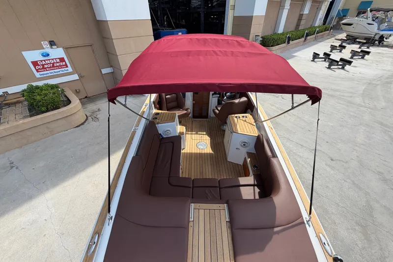 Slide: The Image of 2005 Chris-Craft Corsair 25 boat with red canopy and brown seating, docked outdoors. - 22
