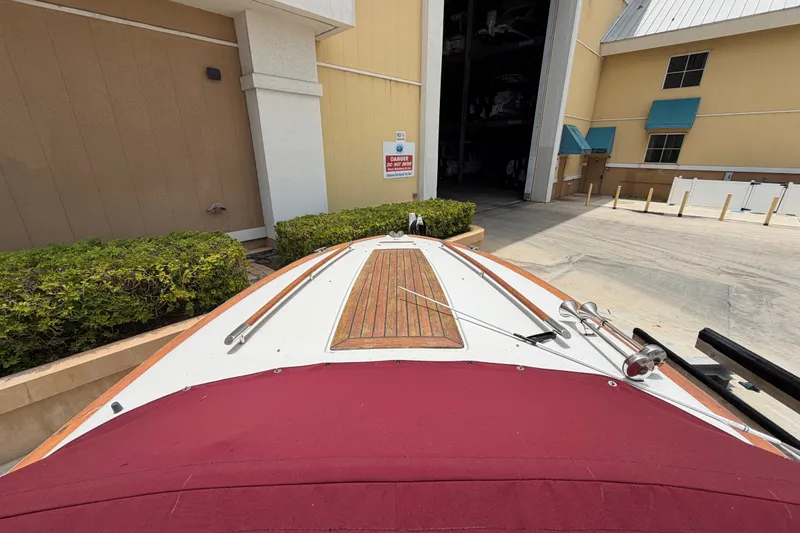 Slide: The Image of 2005 Chris-Craft Corsair 25 boat with wooden deck, docked near a storage facility. - 27
