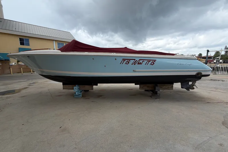 Slide: The Image of 2005 Chris-Craft Corsair 25 boat with red cover, docked on land. - 10