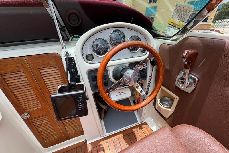 Slide: The Image of 2005 Chris-Craft Corsair 25 cockpit with wooden steering wheel and classic dashboard design. - 34