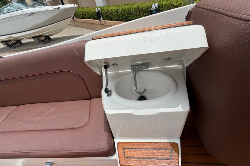Slide: The Image of 2005 Chris-Craft Corsair 25 boat interior with a built-in sink and brown seating. - 44