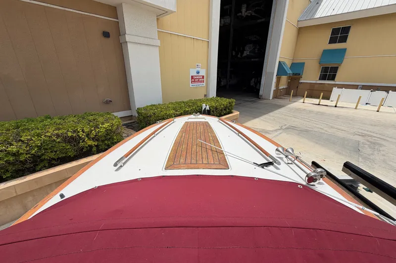 Slide: The Image of 2005 Chris-Craft Corsair 25 boat with red cover, docked near a storage facility. - 26