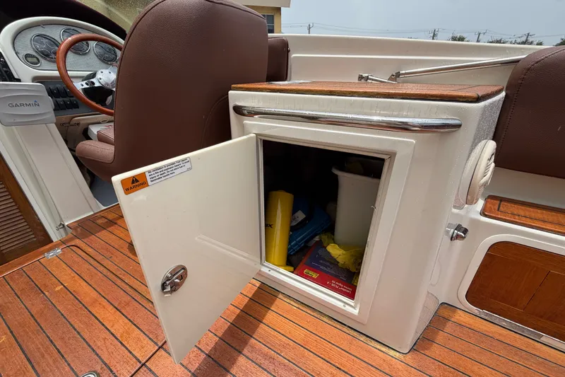 Slide: The Image of 2005 Chris-Craft Corsair 25 boat interior with open storage compartment on wooden deck. - 42