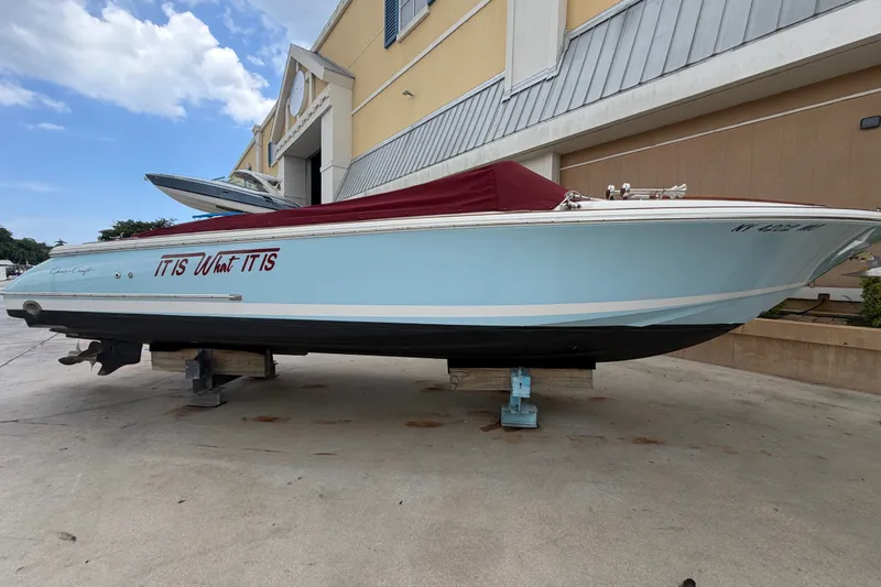 Slide: The Image of 2005 Chris-Craft Corsair 25 boat with blue hull and red cover, docked outdoors. - 2