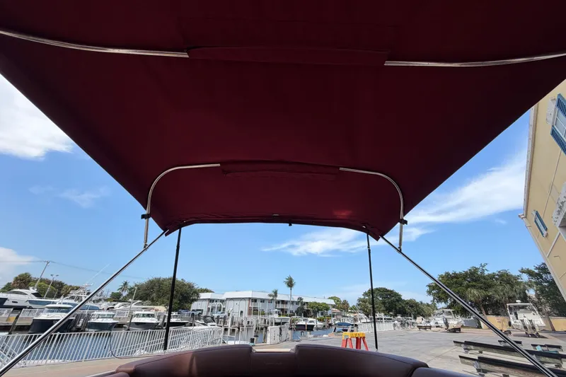 Slide: The Image of 2005 Chris-Craft Corsair 25 with maroon canopy, docked at a marina under a clear sky. - 20