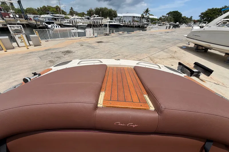 Slide: The Image of 2005 Chris-Craft Corsair 25 boat with brown leather seating and wooden deck, docked at marina. - 23