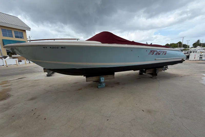 Slide: The Image of 2005 Chris-Craft Corsair 25 boat on dry dock with cover, under cloudy sky. - 9