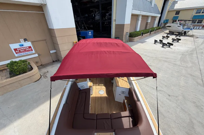 Slide: The Image of 2005 Chris-Craft Corsair 25 with red canopy, docked near a building. - 23
