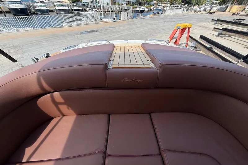 Slide: The Image of 2005 Chris-Craft Corsair 25 boat interior with brown leather seating at a marina. - 30