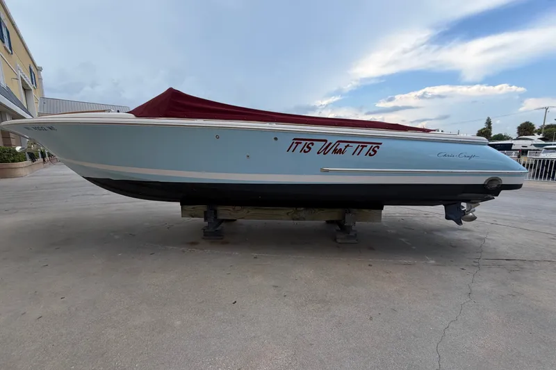 The Image of 2005 Chris-Craft Corsair 25 boat with red cover, docked on land. - 0