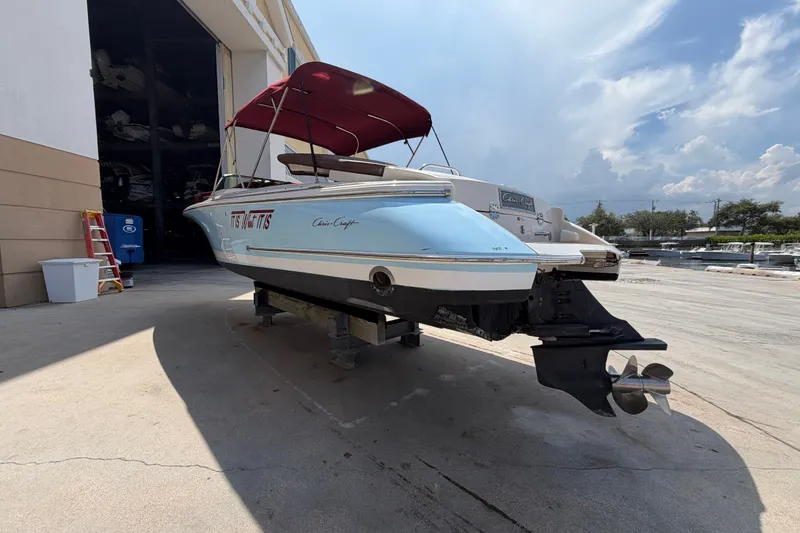 Slide: The Image of 2005 Chris-Craft Corsair 25 boat with red canopy, docked outdoors under a cloudy sky. - 18