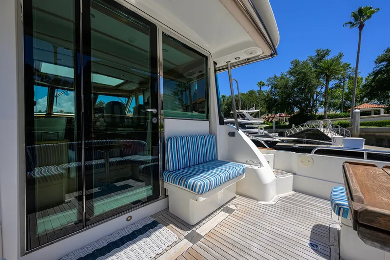 Slide: The Image of 2018 Sabre 45 Salon Express yacht with striped seating and glass doors, docked under clear skies. - 52