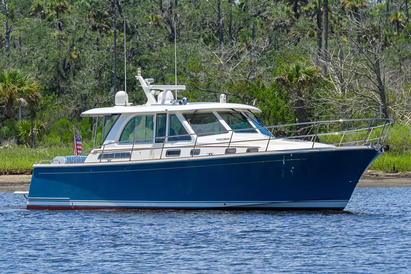 The Image of 2018 Sabre 45 Salon Express yacht on calm water, surrounded by lush greenery. - 0