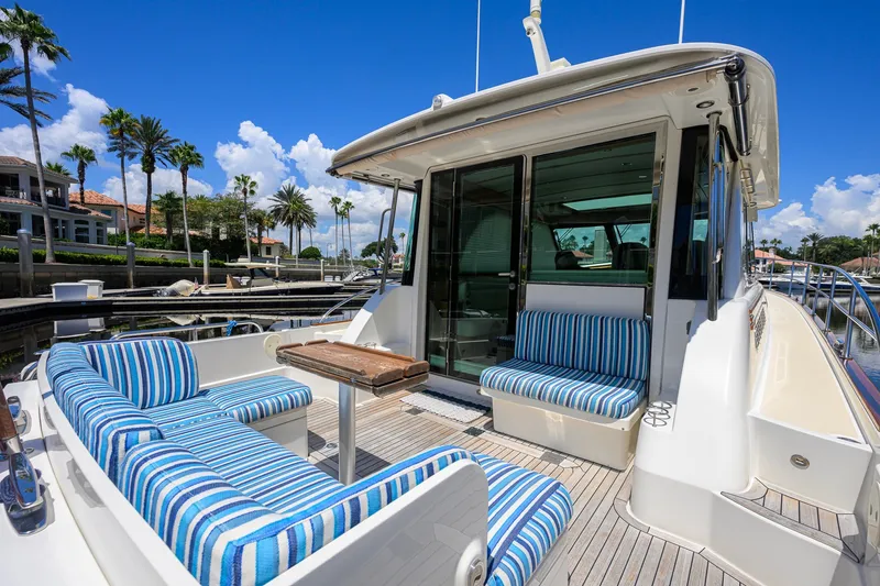 Slide: The Image of 2018 Sabre 45 Salon Express yacht with striped seating, docked under a clear blue sky. - 49