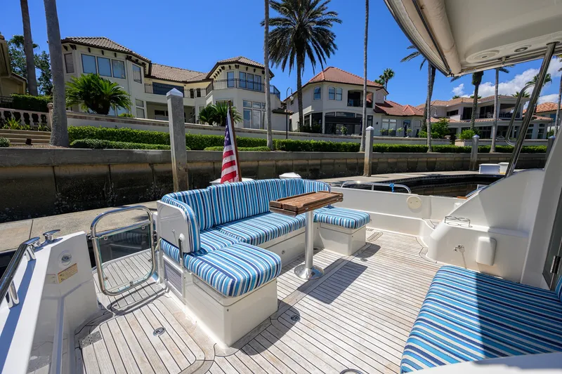 Slide: The Image of 2018 Sabre 45 Salon Express yacht with striped seating, docked near luxury waterfront homes. - 55