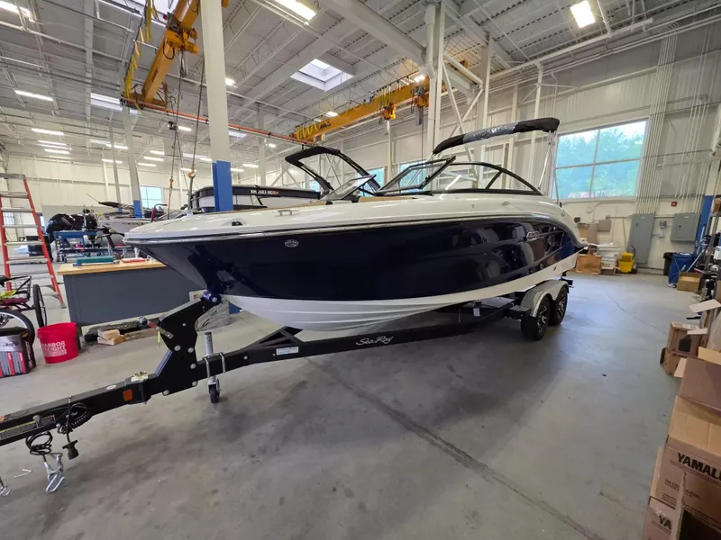 The Image of A 2027 Sea Ray SPX 210 boat sits on a trailer in a spacious warehouse. - 1