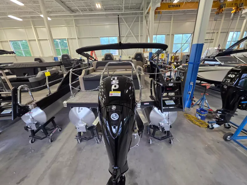 Slide: The Image of The image shows a Barletta ARIA 22UC pontoon boat in a warehouse. It features a black outboard motor. - 6