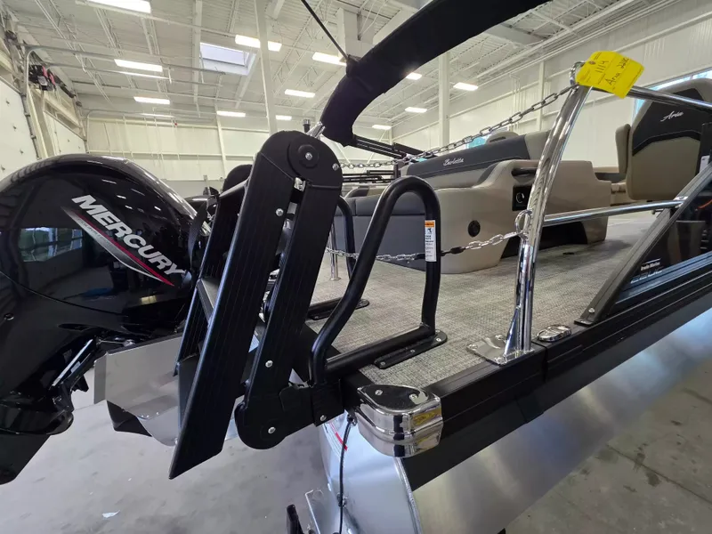 Slide: The Image of The image shows a Barletta ARIA 22UC pontoon boat in a warehouse. A Mercury engine is visible. - 7